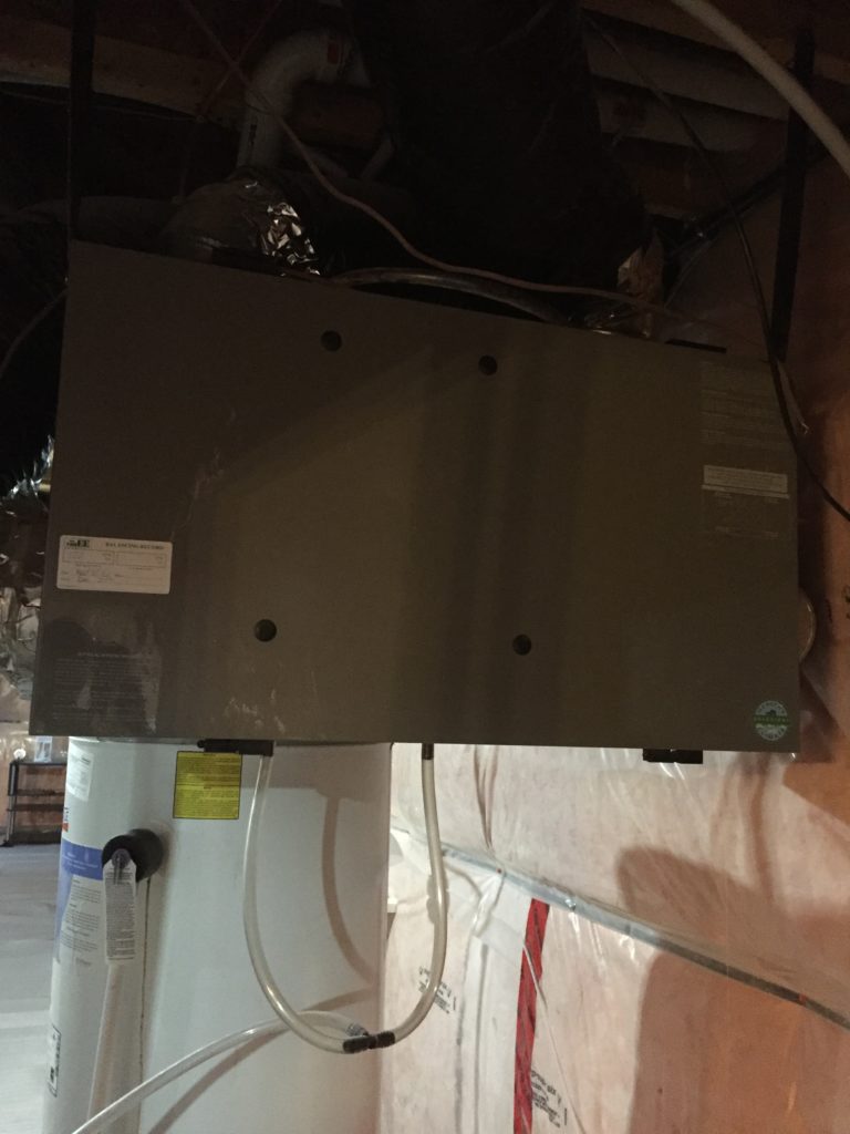 an HRV unit installed in a home, showing cabinet and condensate pipes
